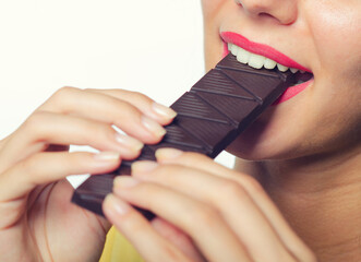 Young woman eating chocolate bar isolated on white background.