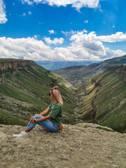 Naklejka premium A girl on the background of the Khunzakh valley, Khunzakh waterfalls, Dagestan 2021