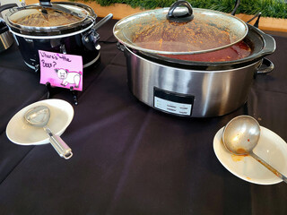 Crockpots on a tablecloth in a chili cook-off contest