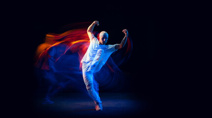 Split personality. Sportive man in sports white uniform and do-rag dancing hip-hop isolated on dark...