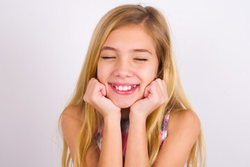 Fototapeta premium little caucasian kid girl wearing sport clothing over white background grins joyfully, imagines something pleasant, copy space. Pleasant emotions concept.