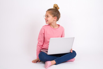 Profile portrait of nice Beautiful caucasian teen girl sitting with laptop in lotus position on white background look empty space toothy smile