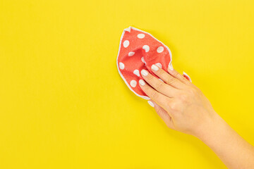 A housewife's hand holds a rag for dusting or washing. Empty space for text or logo on a yellow background. Early spring or regular cleaning. Cleaning and cleaning concept. flat lay