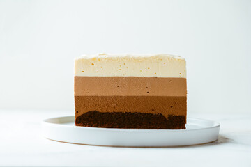 cake cut with sponge biscuit and three chocolate mousse layers. Chocolate mousse cake on the white...