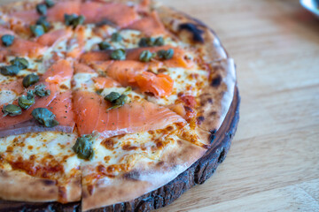 Homemade Smoked Salmon Pizza Topped with Capers, herbs, Dill, Cream Cheese, Tomato sauce and Cracked Peppers (close-up shot). The flatbread with fresh cheese.