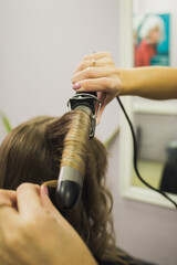 The hairdresser curls his hair. Pokhld to the salon. Hair care. New hairstyle. selective focus.