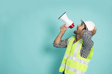 Young professional heavy industry engineer holding megaphone isolated on green background, Speaker...