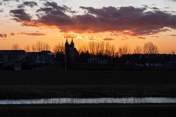 sielski wieczór nad zabudowaniami miejscowości z wieżą kościoła i rzeką © Henryk Niestrój