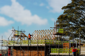 Construction worker placing roof joists in to position and fixing them on new residential house...