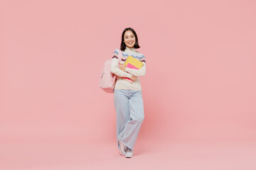 Full body smiling happy cheerful teen student girl of Asian ethnicity in sweater hold backpack book look camera isolated on pastel plain light pink background Education in university college concept