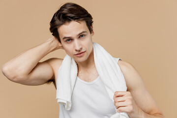 Attractive young smiling handsome fun man 20s perfect skin wearing undershirt towel posing isolated...