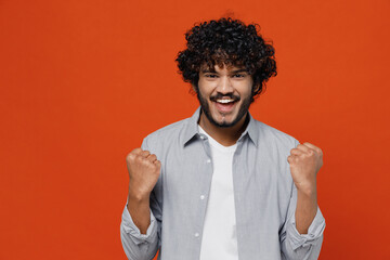Overjoyed jubilant excited exultant young bearded Indian man 20s years old wears blue shirt doing...