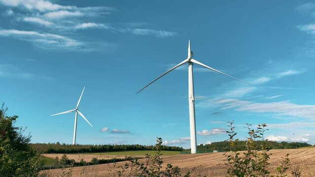 Wind turbine with broken blade not working and awaiting repair on a blue sky background