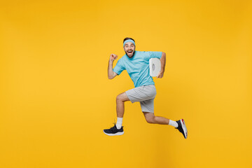 Naklejka na ściany i meble Full size side view strong young fitness trainer instructor sporty man sportsman wear headband blue t-shirt jump high run fast hold scales isolated on plain yellow background Workout sport concept