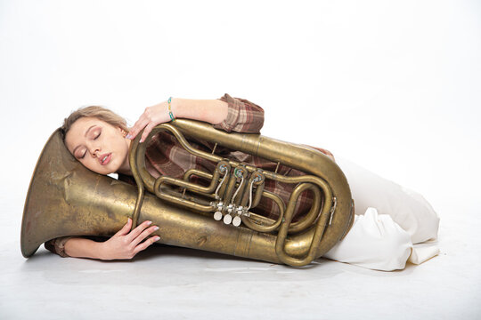 A beautiful girl lies with a musical wind instrument tuba