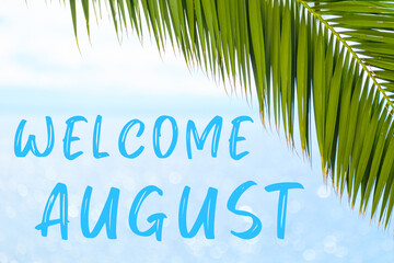 Fototapeta na wymiar Welcome August text on the background with palm leaf and blue sea. Template of a greeting card, postcard or advertisement of a tour agency. 