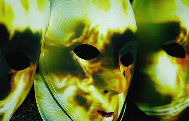 Abstract light strokes, projected over empty scary white masks hanging from a wall in the dark.
