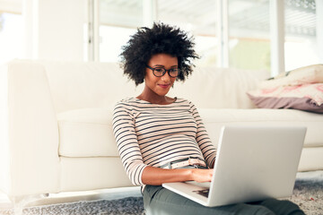 Spending some of her free time online. Cropped shot of a young woman working on her laptop at home.