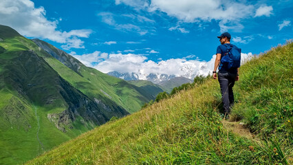Fototapeta na wymiar A male backpacker on a hiking trail to Chubedishi viewpoint. There is an amazing view on the Shkhara Glacier,near the village Ushguli the Greater Caucasus Mountain Range in Georgia, Svaneti Region