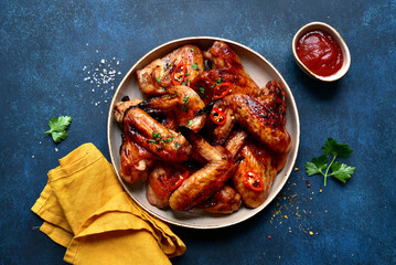 Grilled spicy chicken wings with ketchup . Top view with copy space.