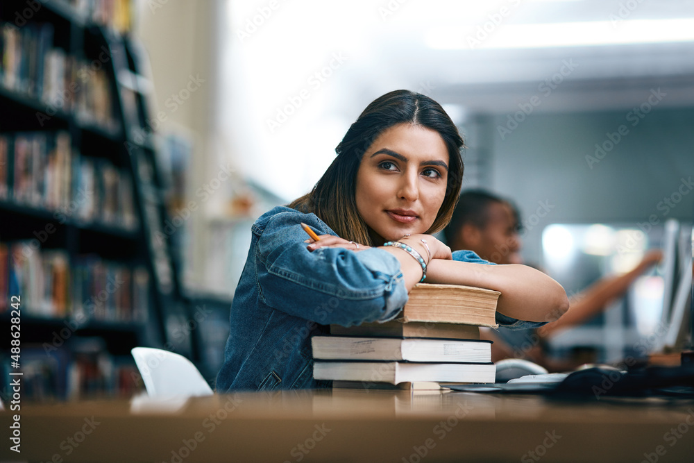Aufkleber where dreams are turned into reality. shot of a young woman resting on a pile of books in a college 