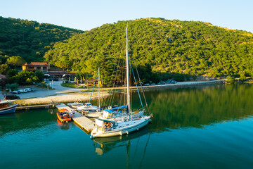 Luxurious yachts moored on marina near oyster farm surrounded by mountains covered with forests....