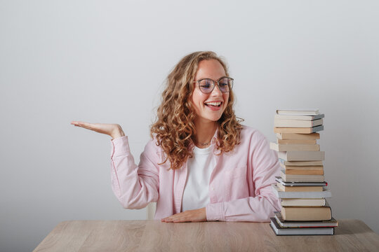 a girl looks at a large stack of books - Powered by Adobe