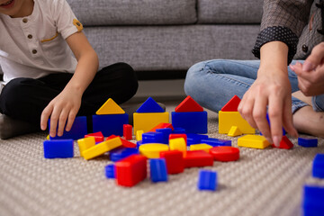 a close-up of a mother and child playing a multi-colored constructor. Early development of the child