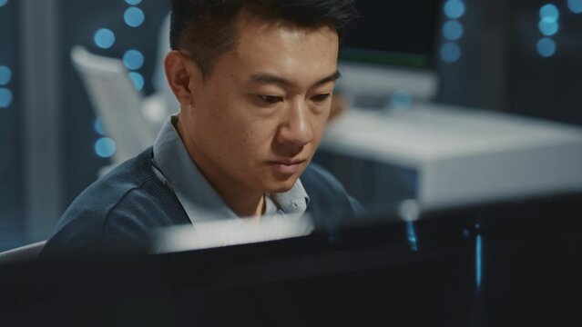 Asian young handsome smart IT specialist working on computer desktop in office. Data center. Database. Cloud computing. Server room.