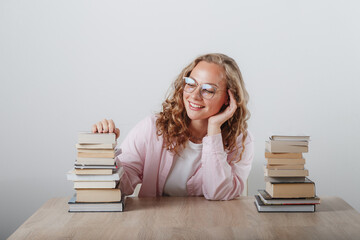 a girl looks at a large stack of books