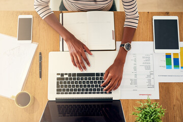 All equipped for a productive day. High angle shot of an unrecognizable woman working on her laptop at home.