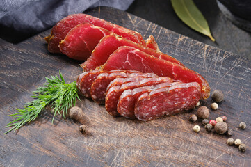 Wooden cutting board with smoked meat 
,prosciutto, salami. Sliced sausage on a kitchen board. Shallow depth of field