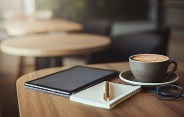 Work from home concept, desk office with digital tablet, blank notepad, eye glasses and coffee cup on wood table