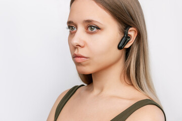 Fototapeta premium Portrait of a young attractive caucasian blonde woman listening to music in black wireless headphones with bone conduction for sports, running, cycling isolated on a white background