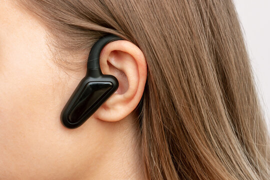 Black Wireless Headphones With Bone Conduction For Sports, Running, Cycling On A Head Of A Young Woman Listening To Music. Close Up