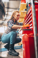 Female auto mechanic. beautiful young red-headed girl in working process at auto service station,...