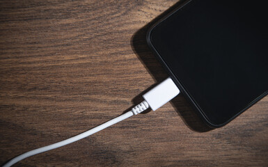 Smartphone charging battery on the wooden table.