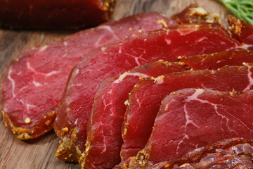 Wooden cutting board with smoked meat, prosciutto. Sliced sausage on a kitchen board. Shallow depth of field