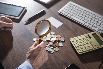 Male hand magnifying coins. Inspect income