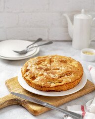 Traditional apple pie on a white plate on a light culinary background. Charlotte pie on a platter closeup. Delicious homemade cakes on the kitchen table