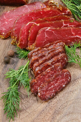 Wooden cutting board with smoked meat or sausage, prosciutto, salami. Sliced sausage on a kitchen board. Shallow depth of field