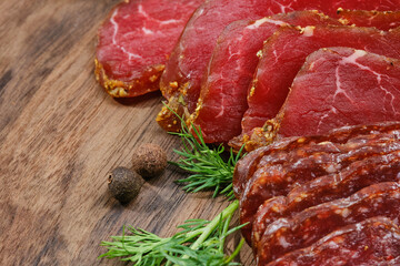 Wooden cutting board with smoked meat or prosciutto, salami. Sliced sausage on a kitchen board. Shallow depth of field