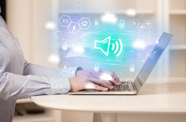 Hands working on laptop with digital icons