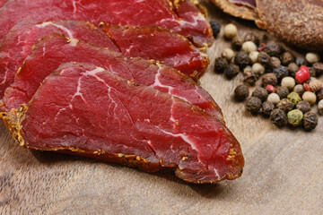 Wooden cutting board with smoked meat, prosciutto. Sliced sausage on a kitchen board. Shallow depth of field