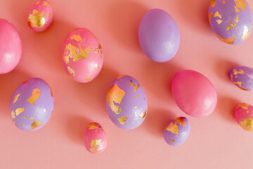 Easter colored eggs with golden foil on the pink pastel background. 