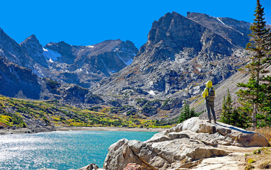 Hiker looks out at Isabelle Lake and the Rocky Mountains in the Indian Peaks Wilderness, Boulder County, Colorado.