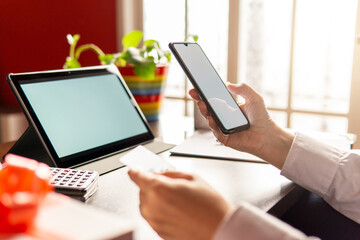 Woman using smartphone with credit card, ordering online shopping. Working from home concept