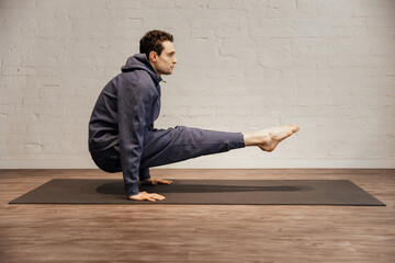 Fototapeta premium Young strong shirtless man practices yoga at the yoga studio