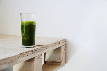 Glass with green juice on a slightly grimy white table