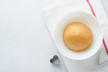 Baking ingredients and kitchen utensils on a white background top view. Preparing heart sugar cookies. Baking background. Flour, eggs, sugar, spices, and a whisk on the kitchen table. Flat lay.